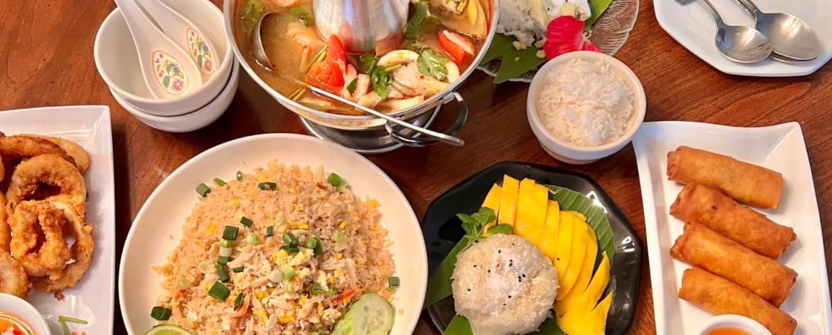 A spread of Thai dishes on a wooden table at Pad Thai Café